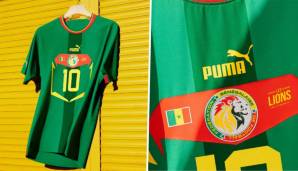 SENEGAL (Auswärtstrikot): Das Auswärtstrikot Senegals ähnelt anderen Designs von Puma. Es ist überwiegend grün, blitzt an Kragen und Ärmeln in Rot und Gelb auf. Der Spitzname "Les Lions de la Teranga" ist im zentralen Nummernfeld platziert.